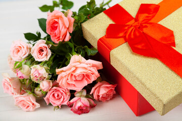 Bouquet of pink roses in a red box on a wooden background.