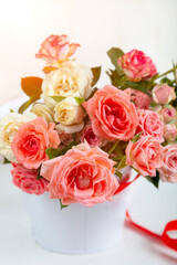 Bouquet of pink roses in a vase with a ribbon on a wooden background.