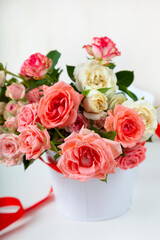 Bouquet of pink roses in a vase with a ribbon on a wooden background.