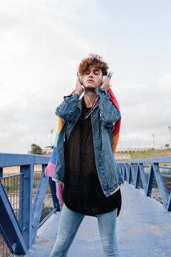 Gay man with rainbow flag listening to music in headphones