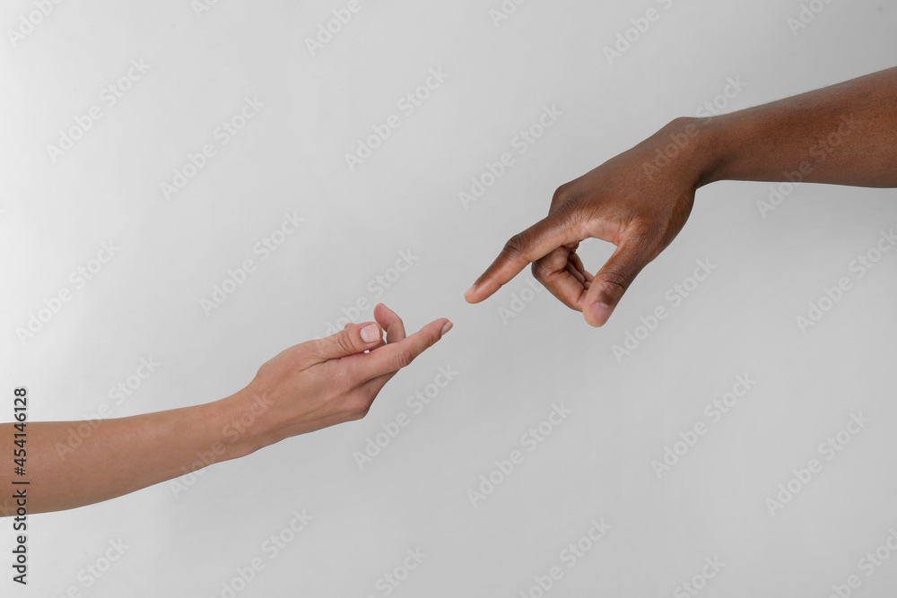 Wall mural woman and african american man touching fingers on light grey background, closeup