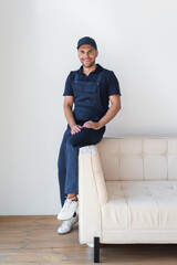 happy worker in overalls smiling at camera on white couch