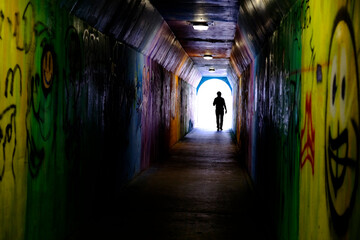 Man Walking Through Graffiti Tunnel Towards the LIght
