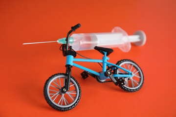 Bike model and syringe on red background. Using doping in cycling sport concept