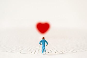 Miniature people group runner running to entrance of maze on white background with copy space finding Red Heart for Healthy lifestyle and sport gym body fitness medicine health care avoid COVID-19 