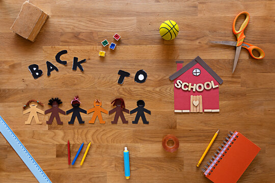 Racial school segregation illustrated through a black ethnicity human paper chain and some school supplies on the frame during back to school