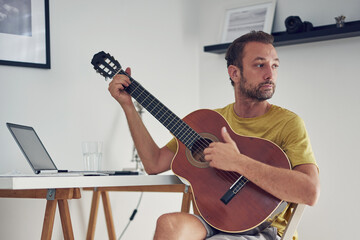 Man playing acoustic guitar at home.