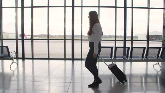 business woman from the side in an airport with a suitcase