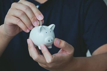 Money saving concept, people putting coin money on the piggy bank.