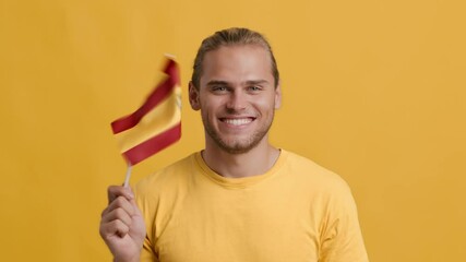 Handsome young patriotic guy waving with flag of Spain, smiling at camera - Powered by Adobe