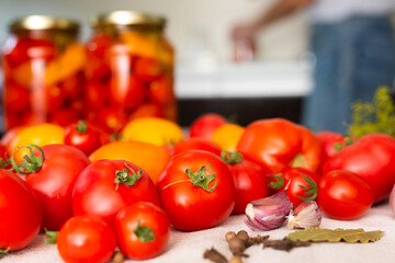 fresh red tomatoes, spices, seasonings and pickled tomatoes in jars on the table