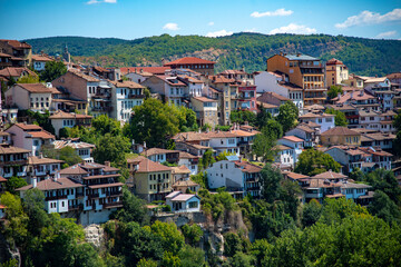 Fototapeta na wymiar Houses with red tiled roofs , built on a mountain under a bright blue sky.Veliko Tarnovo in a beautiful summer day, Bulgaria