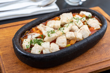 diced sea bass in casserole on wooden cutting board