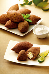 kibes dispostos sobre mesa de madeira acompanhado de coalhada seco e limão 