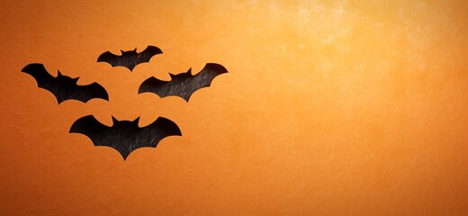 Fototapeta premium Warm orange Halloween background with black bat silhouettes. Carved out bat shapes revealing crumpled black paper. Seasonal backdrop with space for copy.