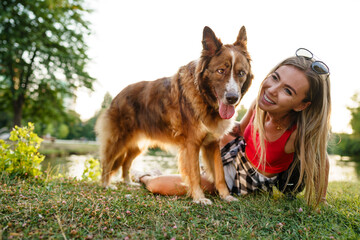 Close up of young female with her dog sitting on grass in park
