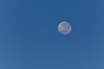 A full moon in the blue sky.