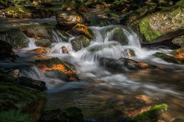 sunlit cascade and boulders in a mountain stream