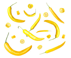 Ripe yellow chili peppers falling on white background