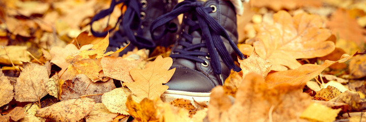 children's feet in shoes in a pile of autumn fallen orange leaves in an fall forest or park....