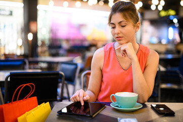 Young woman on a coffee break. Using tablet computer.