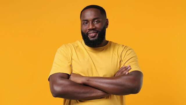 Chaming charismatic young bearded african american man 20s years old wears orange t-shirt looking camera smiling isolated on plain yellow background studio portrait. People emotions lifestyle concept