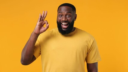 Smiling cheerful blithesome charismatic young bearded african american man 20s years old wears orange t-shirt showing okay ok zero fingers gesture isolated on plain yellow background studio portrait