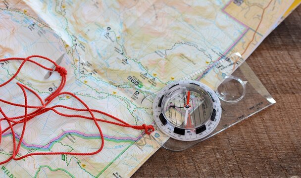 Compass and map used to hike trails, travel and explore, discover, and navigate the great outdoors.