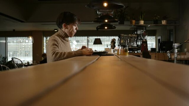 side view A lonely girl drinking coffee and eating salad sitting at a restaurant table. Video for advertising cafe. High quality FullHD footage