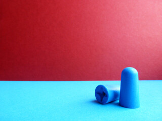Pair of blue earplugs on a burgundy-blue blur background