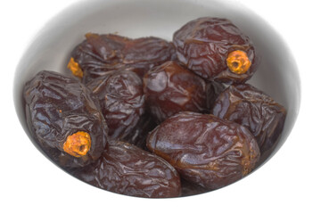 Several royal dates in a white ceramic dish, close-up, isolated on white.