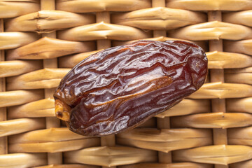One royal date on a vine mat, close-up, top view.