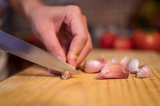 Crop woman cutting garlic at table