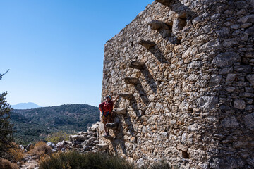 woman in red against the background of old dilapidated mills on the island of Crete 