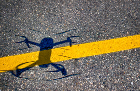 Shadow Of A Drone Hovering Over Asphalt