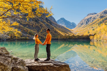 Couple posing at lake in the autumnal mountains. Mountain lake and couple hikers