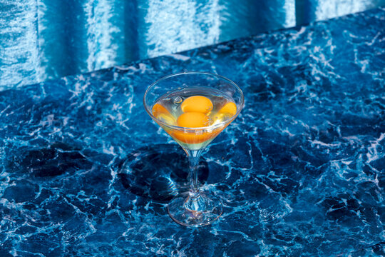 Glass with raw eggs on table