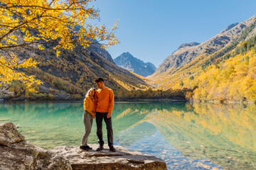 Couple posing at lake in the autumnal mountains. Mountain lake and couple hikers