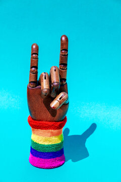 Hand with horn gesture and LGBTQ ornament on wristband