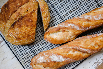 Fresh baked bread and baguettes on a cooling rack in a bakery.