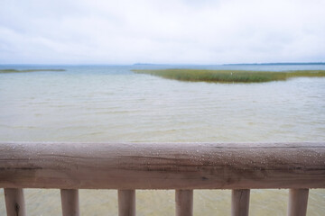 Wooden fence on a storm lake background. Hewn pine log in the rain.