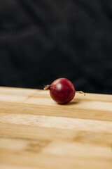 Gooseberry. One red berry. One gooseberry berry on a wooden surface. Plenty of space for text