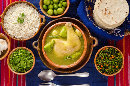 Top view of "Jocón", a traditional dish of Guatemala cuisine, made with green sauce, vegetables, and chicken, served with rice and tortillas.