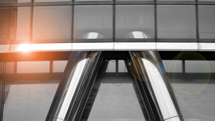 Obraz premium Modern architectural details. Modern glass facade with a geometric pattern. Contemporary corporate business architecture. Red sun on horizon. Black and white toned image.