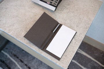 White paper and pen on the leather board. Hotel notepad on a marble countertop, next to a wired...