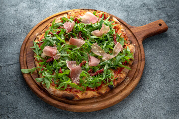 Tasty hot italian pizza Prosciutto with Parma ham, Cheese Mozzarella, Conkasse, Tomatoes, Arugula, Tomato Sauce. Pizzeria menu.