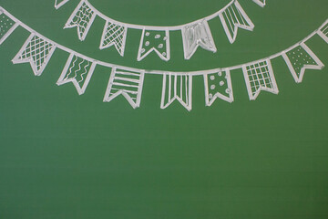 A garland of flags drawn in white chalk on a green blackboard and a space for copying. Concept - back to school and holiday