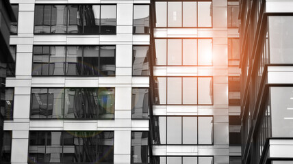 Modern architectural details. Modern glass facade with a geometric pattern. Contemporary corporate business architecture. Red sun on horizon. Black and white toned image.