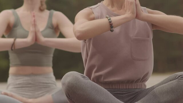 Midsection of two pairs of female hands in praying position during meditation outdoors on windy day