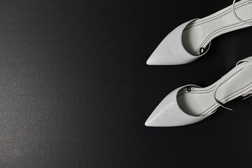 White high heels on black background.